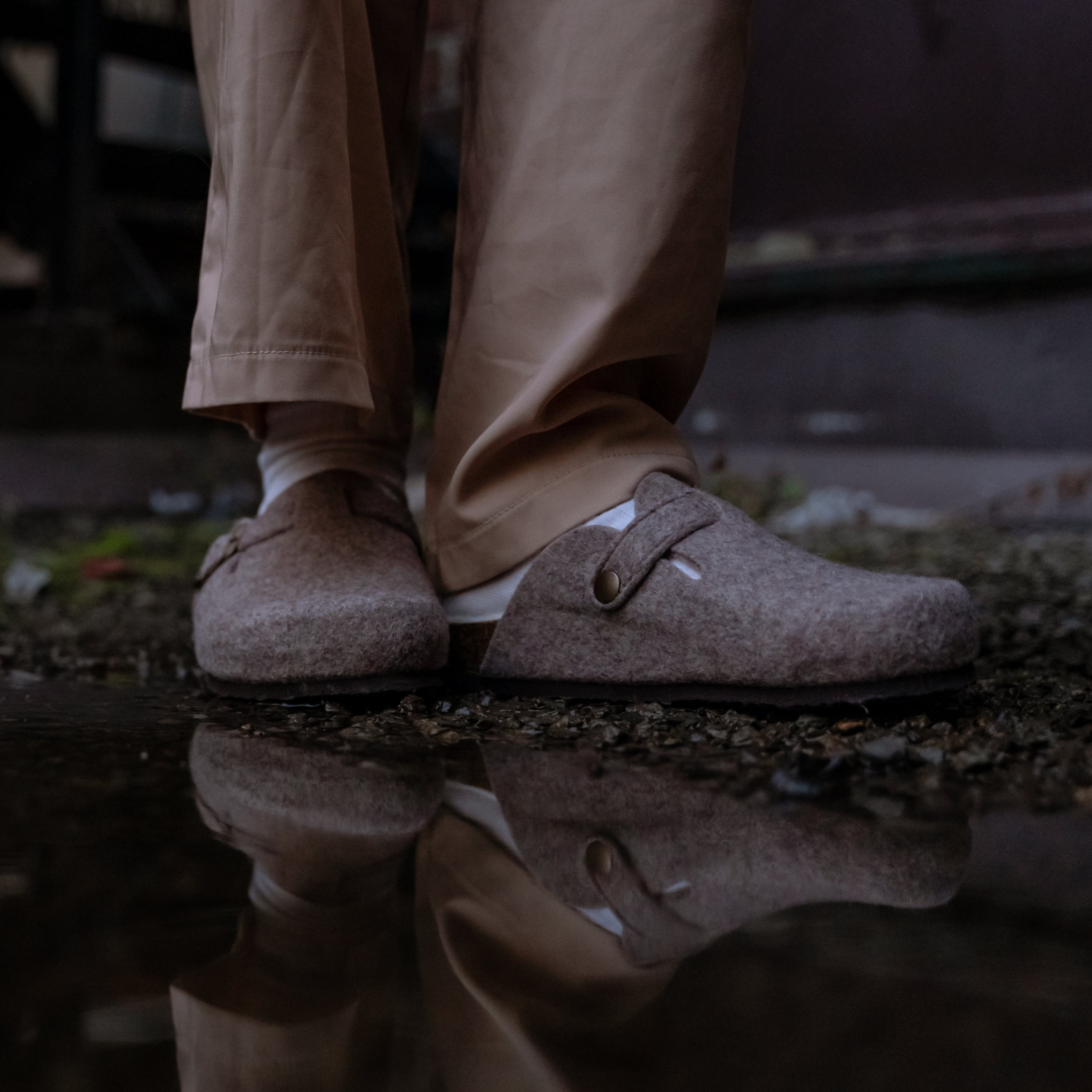 Person wearing beige shoes and pants standing near water with reflection