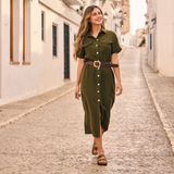 Woman walking along a sunlit cobblestone street in a charming Spanish town during golden hour, wearing comfortable Plakton cork footbed sandals handmade in Spain, styled with a relaxed summer dress.