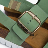 Macro detail of the Plakton Condor sandal, focusing on the large polished silver buckle on a mint nubuck strap and the "Made in Spain" logo embossed on the natural cork footbed.