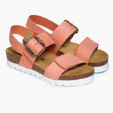 A pair of Condor Platform sandals angled to showcase the deep anatomical heel cups and the impressive handcrafted cork midsole. The dual adjustable peach straps feature brushed metallic buckles and rest atop a plush suede lining, reflecting the "Nature’s Hug" philosophy where bold Mediterranean style meets the purity of the earth.