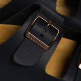 An extreme close-up of the Beta strap, focusing on the fine, velvety grain of the Soft Black nubuck leather. A sturdy dark metallic buckle embossed with "PLAKTON" is the centerpiece, while the soft-focus background highlights the porous, sustainable cork, emphasizing the premium "Handmade in Spain" heritage.