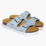 A pair of Beta sandals in Soft Blue, angled to highlight the deep-seated heel cups and the smooth transition of the handcrafted cork base. The dual adjustable nubuck straps feature brushed metallic buckles, resting atop a plush tan suede lining that emphasizes the signature Plakton "Nature’s Hug" philosophy.