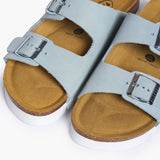 An overhead view looking directly into the Beta footbeds. The image captures the natural width of the cork base and the prominent "Plakton Memory Cushion" branding at the heel. The buckled Soft Blue straps frame the hand-sculpted contours, illustrating a design built for anatomical support and total freedom of movement.