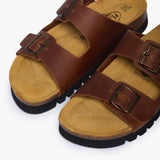 An overhead view looking directly into the Beta footbeds. The image highlights the natural width of the cork base and the prominent "Plakton Memory Cushion" branding at the heel. The buckled Brown Oil Leather straps frame the hand-sculpted contours, illustrating a design that honors the foot’s natural shape.