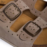 An extreme close-up focusing on the velvety texture of the taupe suede and the precision-set metallic studs of the CP Beta. A sturdy buckle embossed with "PLAKTON" anchors the strap, while the soft-focus background highlights the porous, breathable grain of the natural Spanish cork, signifying premium handcrafted quality.