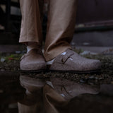 Person wearing beige shoes and pants standing near water with reflection