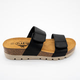 Black Plakton Cult sandal with two wide leather straps featuring Velcro closures, cork and Memory Foam footbed, and a beige lightweight sole.